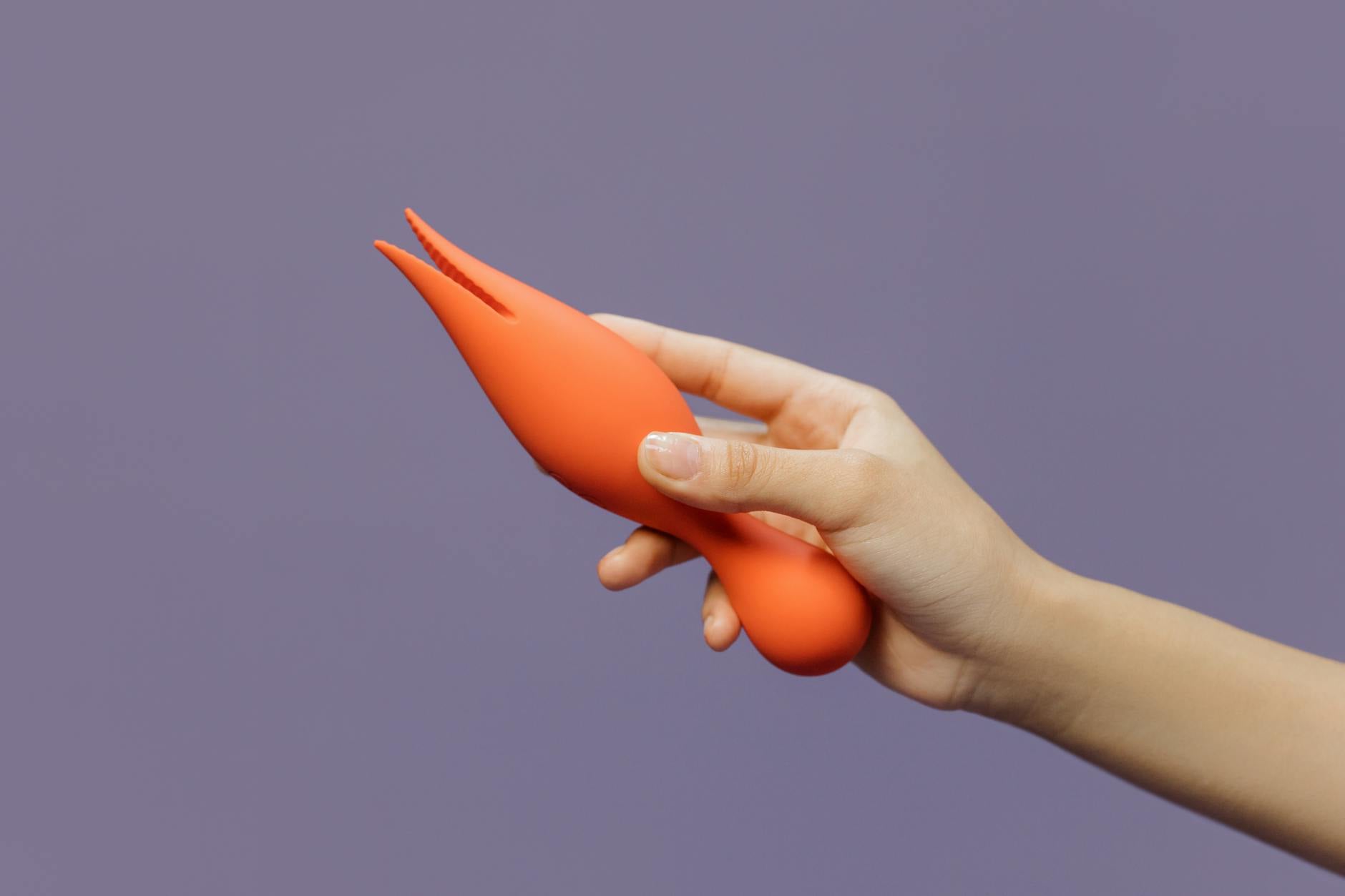 Close-up of a hand holding a lemon-colored vibrator against a purple background, symbolizing modern sensuality and intimate connection.